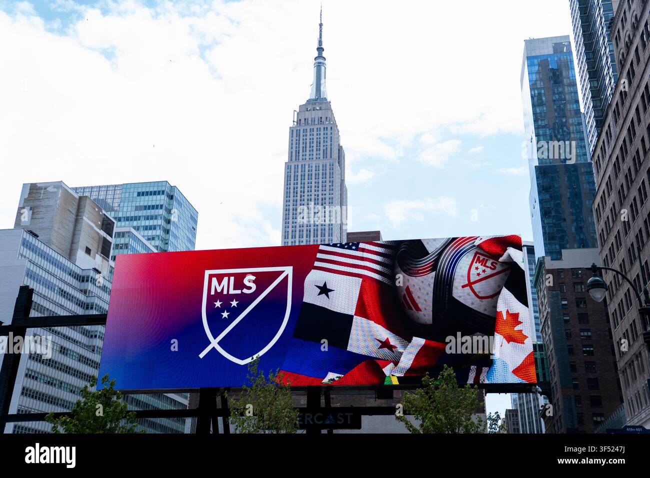 New York City, USA - 20. Juli 2026: Das Empire State Building erhebt sich über Midtown Manhattan, während eine digitale Werbetafel der Major League Soccer (MLS) angezeigt wird Stockfoto
