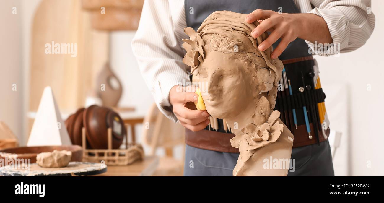 Künstlervie sculptieren einen Tonkopf einer Frau mit kunstvollen Details und Blumenelementen in einem Töpferatelier Stockfoto