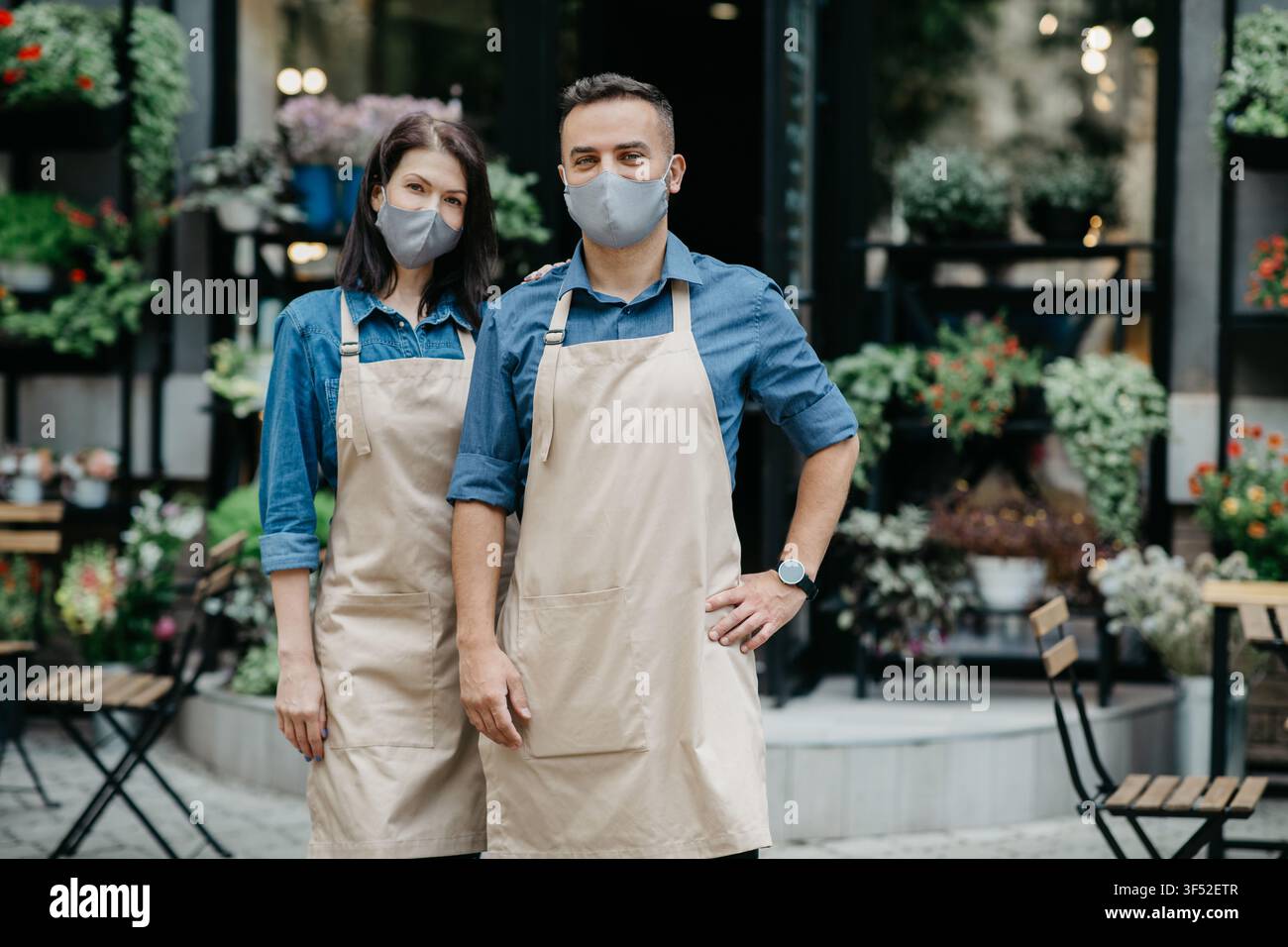 Family Startup und florales Design. Guy und Mädchen stehen auf Blumengeschäft Hintergrund Stockfoto