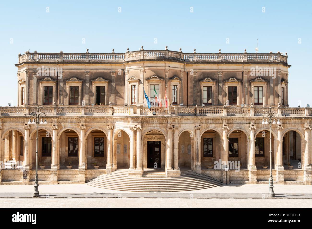 Frontansicht der barocken Fassade des Palazzo Ducezio, der das Rathaus von Noto in Sizilien beherbergt, an einem klaren Sommertag Stockfoto