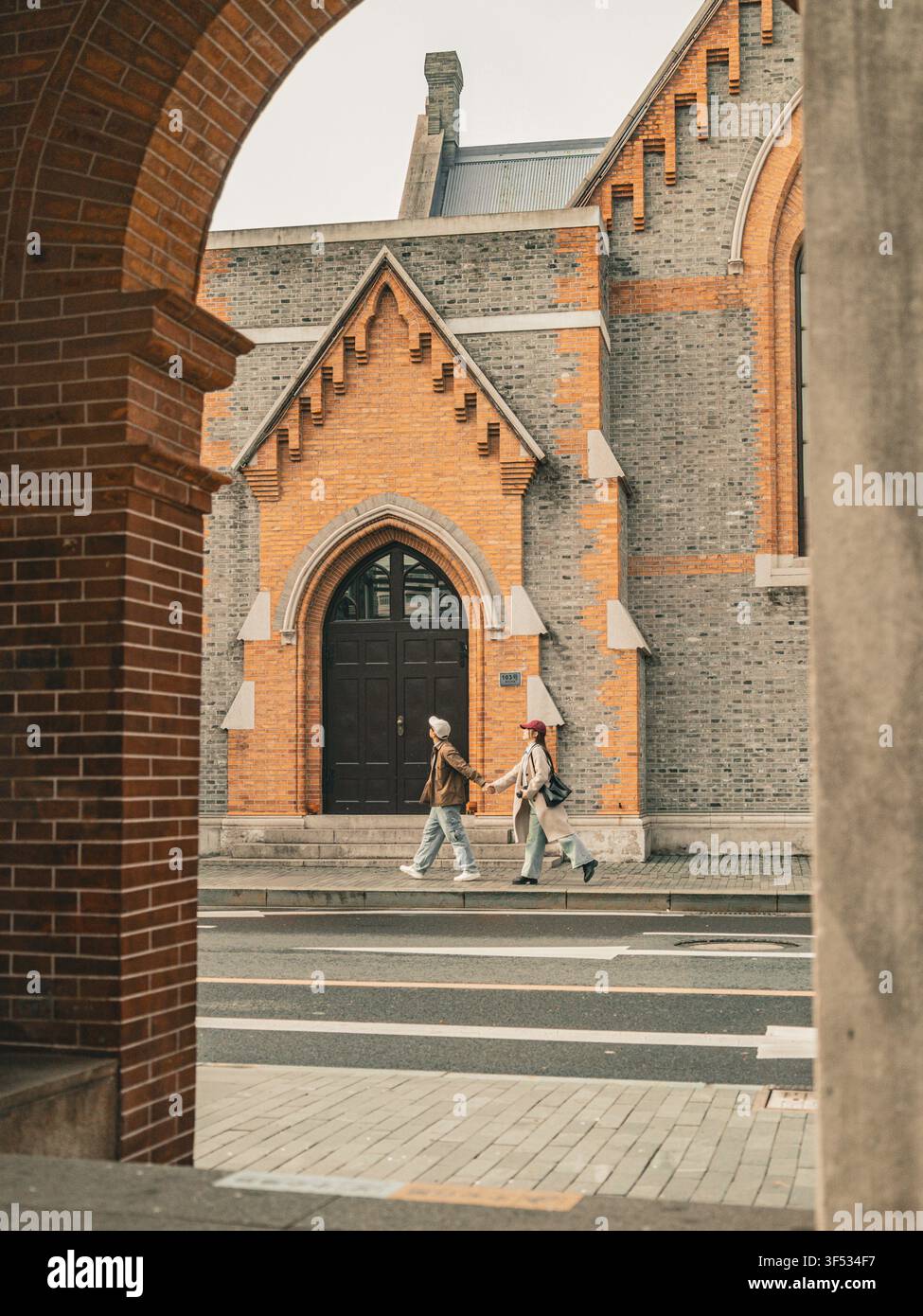 Paar, das sich an den Händen hält und vor der Union Church in Shanghai die Straße überquert Stockfoto