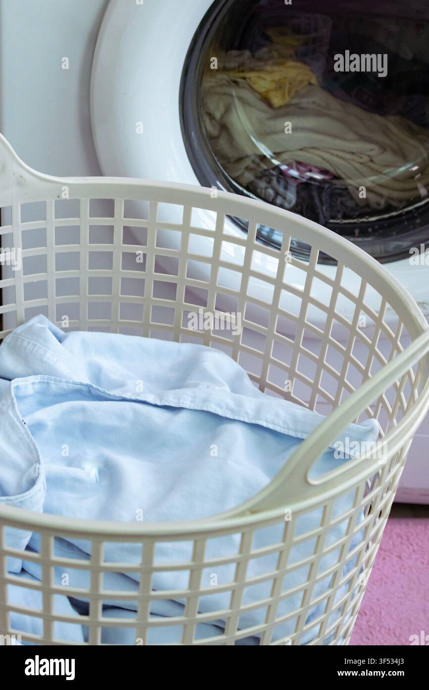 Wäschekorb mit frisch gewaschener Wäsche in der Nähe der Waschmaschine – Konzept für die Heimwaschroutine Stockfoto