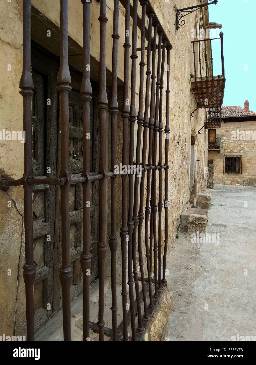 Nahaufnahme eines alten Fensters mit traditionellen schmiedeeisernen Gittern in einer Kopfsteinpflasterstraße im mittelalterlichen Dorf Pedraza, Segovia, Spanien Stockfoto