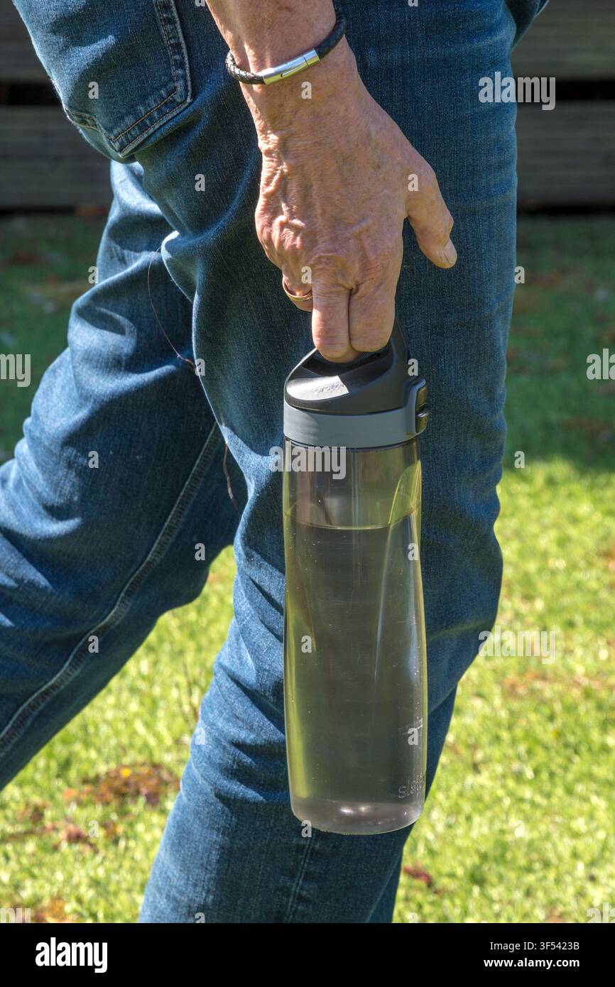 Frau trägt eine Wasserflasche, um mit der extremen Hitze im Juli 2026 zurechtzukommen. Stockfoto