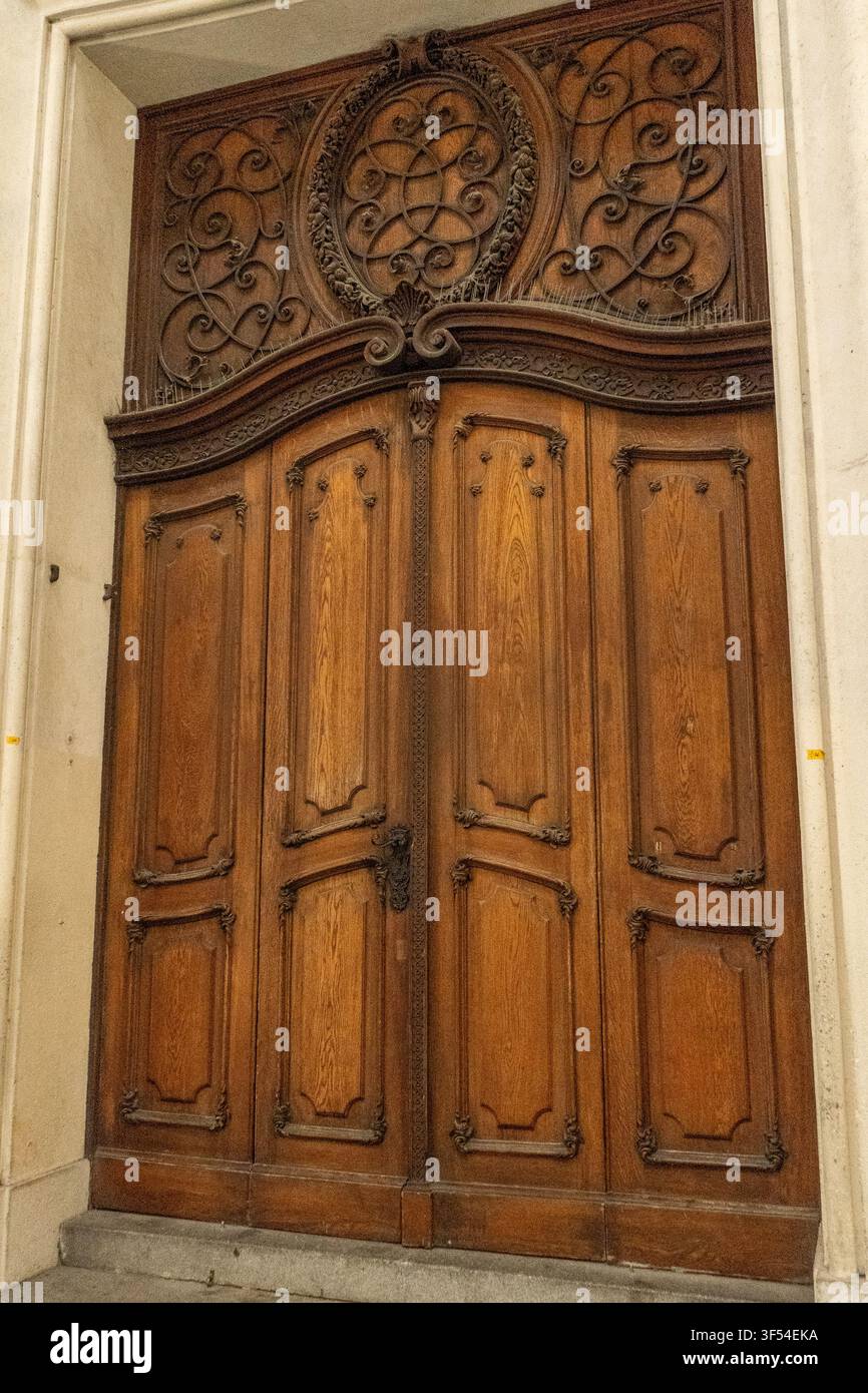 Verziertes Holzportal mit geschnitzter Oberlichtplatte am Eingang eines historischen Gebäudes in Wien, Österreich. Stockfoto
