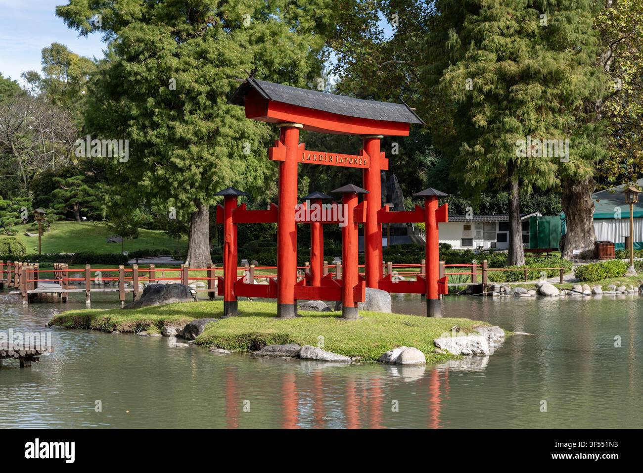 Ein lebendiges Tagesfoto des traditionellen roten Torii-Tors, das mitten in einem ruhigen See im Japanischen Garten in Buenos Aires, Argentinien, steht Stockfoto