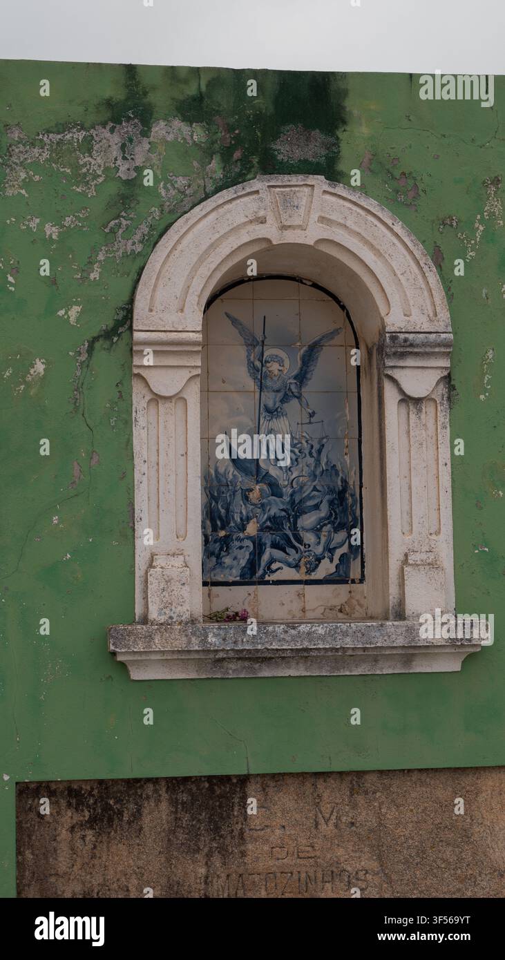 Blaues und weißes Azulejo-Panel von Saint Michael, der den Teufel in einer Steinnische erschlägt, Portugal — Konzept: Portugiesischer Volkskatholizismus, Straßenaltäre Stockfoto