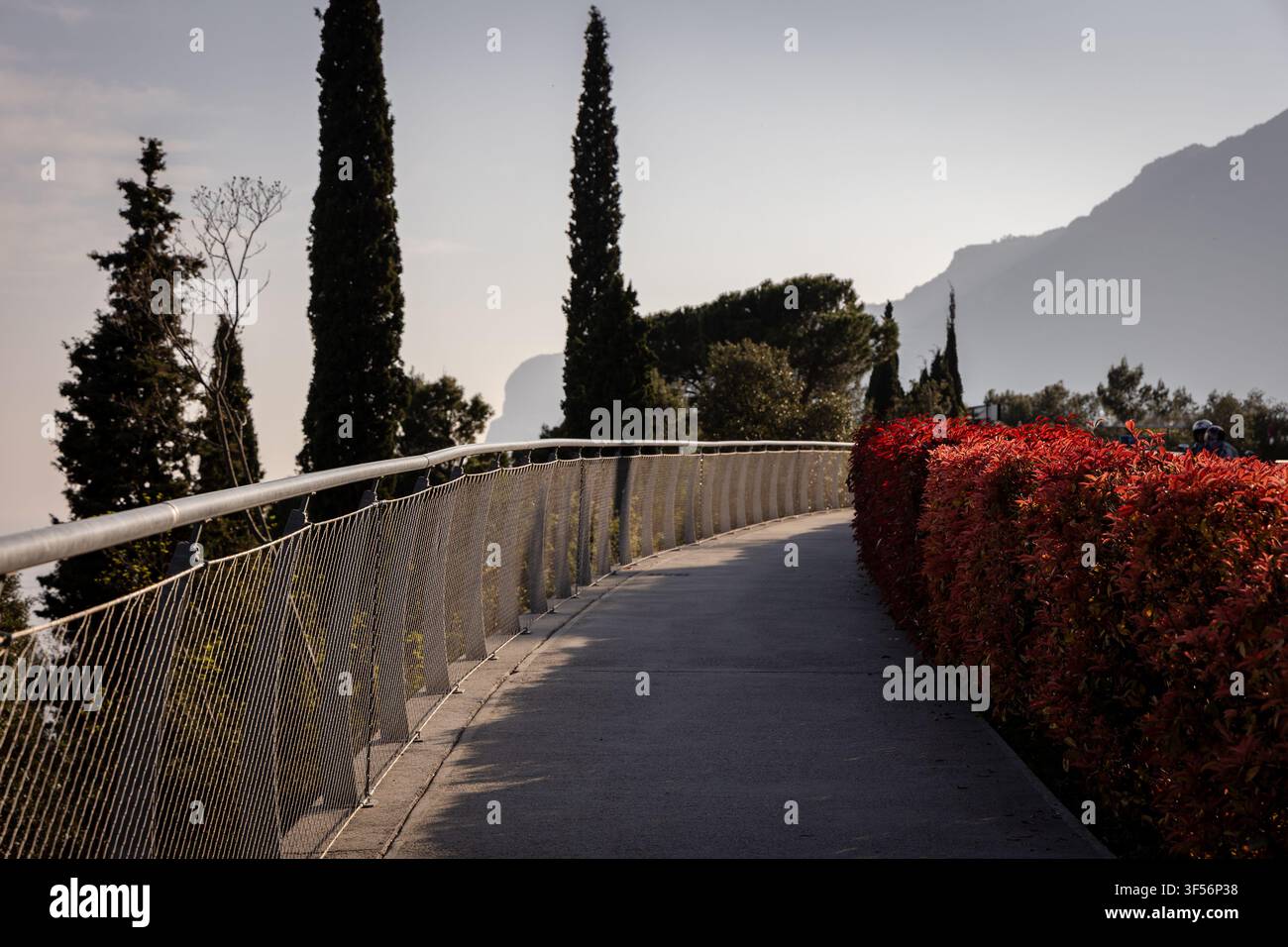 Pittoresker erhöhter Fußgängersteg mit Blick auf den Gardasee, Zypressen und mediterraner Landschaft in Limone sul Garda, Italien. Stockfoto