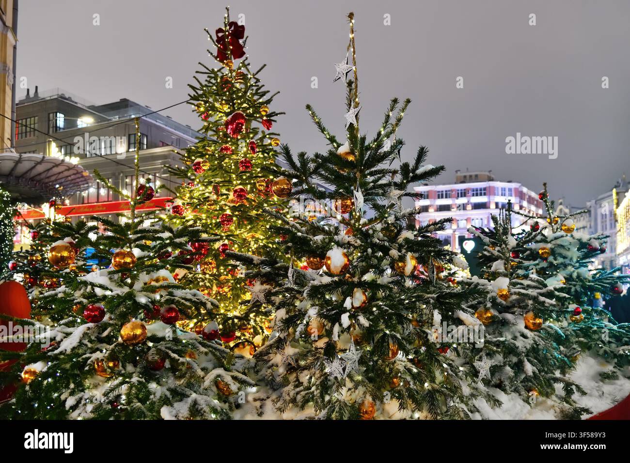 Weihnachtsbäume, die mit farbenfrohen Kugeln und Neon-Girlanden geschmückt sind, in der Nacht auf der Straße der Stadt. Hintergrund für Weihnachten und Neujahr Stockfoto