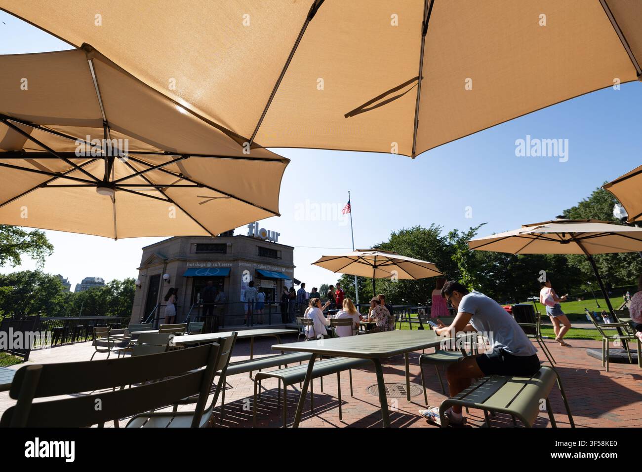Besucher sitzen unter Sonnenschirmen in einem Außenbereich eines Cafés im Boston Common, Boston, Massachusetts. Stockfoto