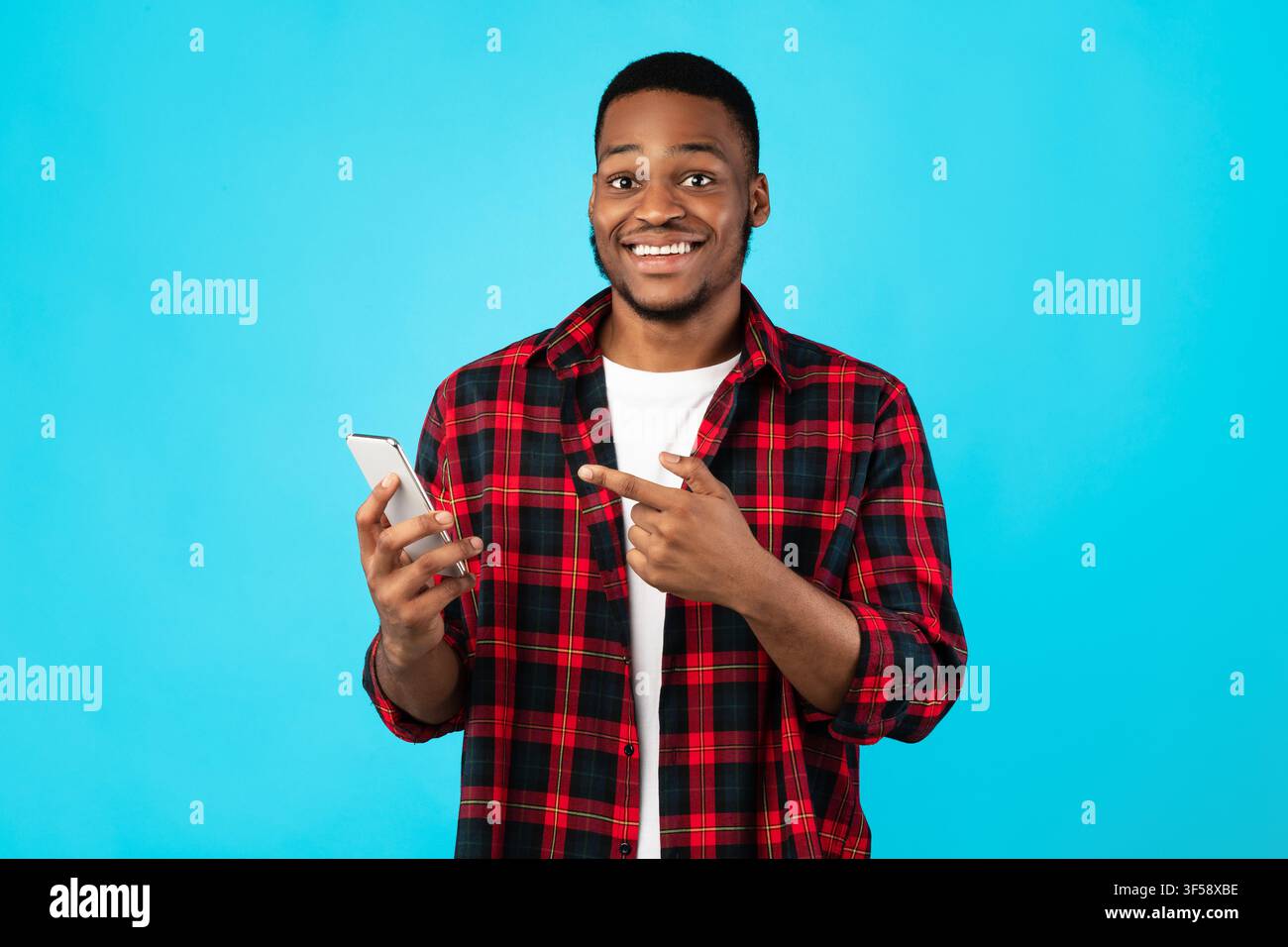 African Guy Zeigt Finger Auf Smartphone Stehen Über Blauen Hintergrund Stockfoto