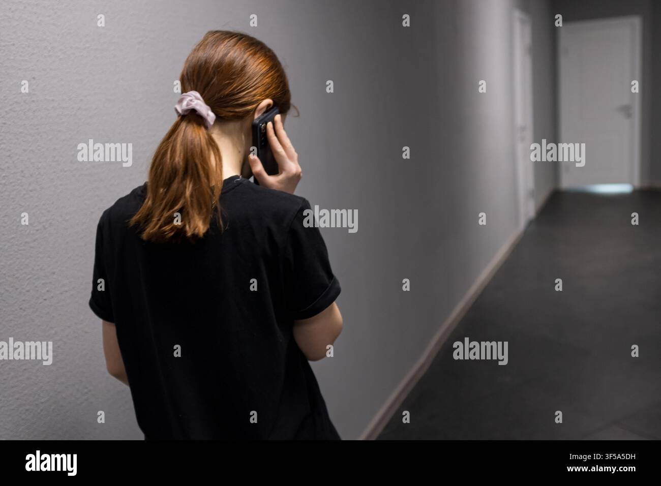 Frau telefoniert und sucht Privatsphäre im Korridor Stockfoto