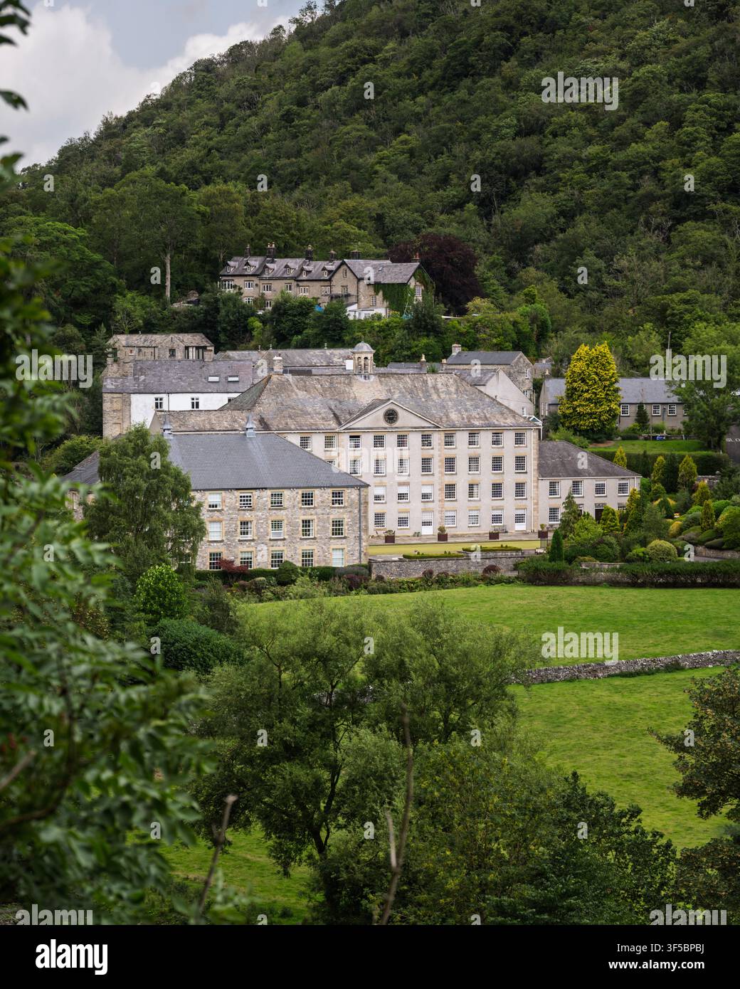 Die historische Steinbauweise von Cressbrook Mill steht eingebettet im üppigen grünen Tal von Millers Dale entlang des Monsal Trails, Peak District, England Stockfoto