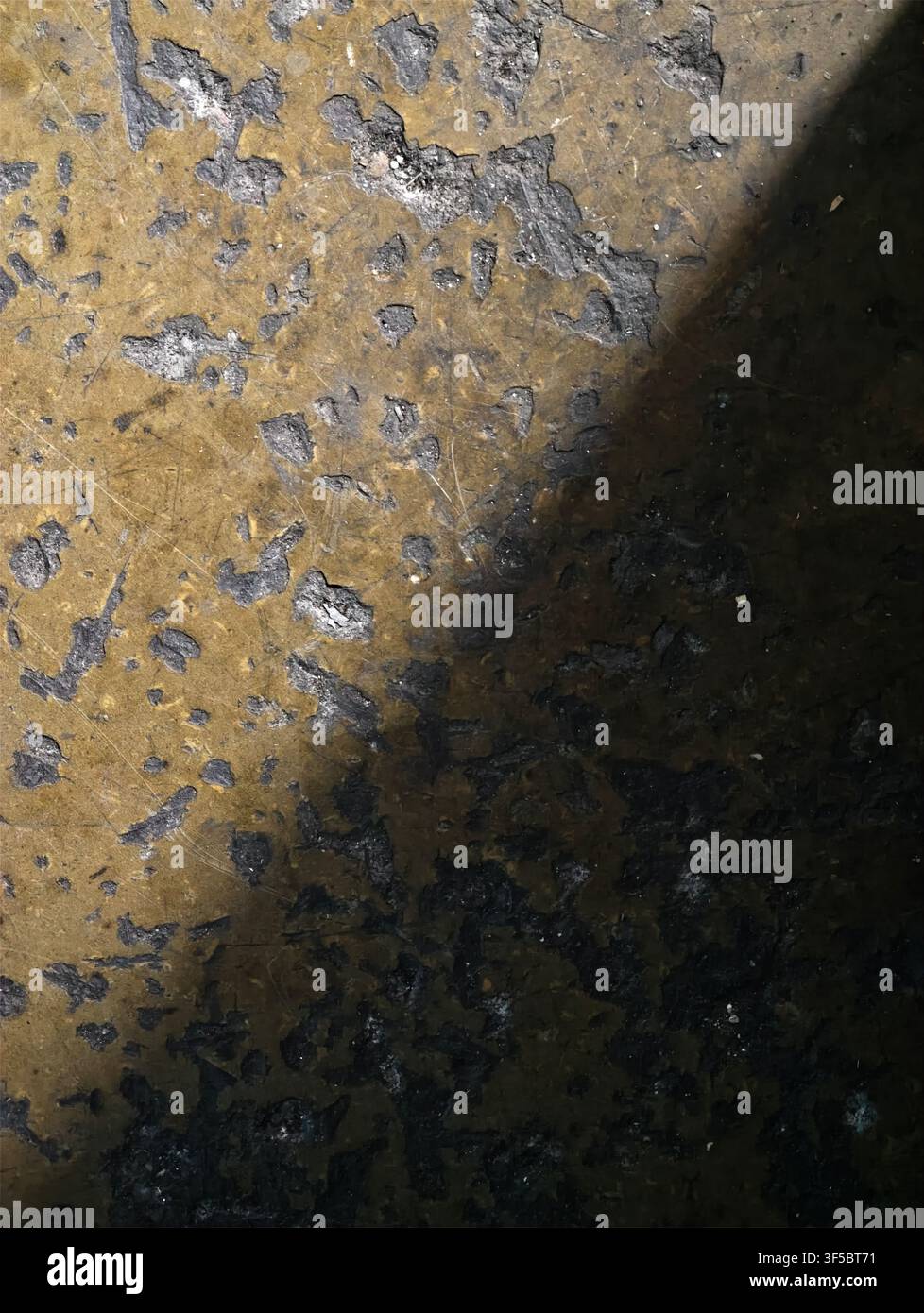 Nahaufnahme einer verwitterten Metallplatte, die gelbe Ockerfarbe abblättert, dunkle Rostflecken, graue Korrosion und eine raue Oberflächendetails mit Alterung zeigt Stockfoto