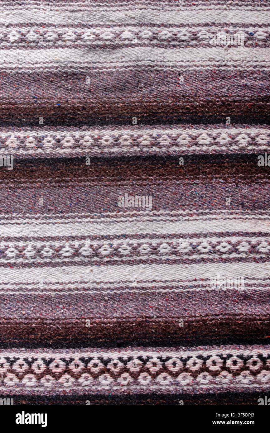 Handgefertigte gewebte grobe Flor lila gemusterte Streuteppich-Hintergrundkulisse Stockfoto