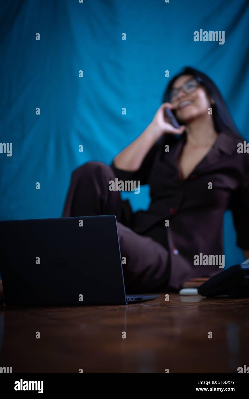 Frau, die einen Anruf tätigt und aus der Ferne mit einem Laptop arbeitet Stockfoto