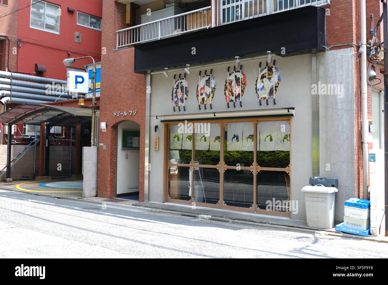 Ein traditionelles japanisches Restaurant mit einer Fassade, die mit dekorativen runden Kunstwerken über Schiebetüren aus Glas entlang einer Straße in Tokio geschmückt ist, Stockfoto
