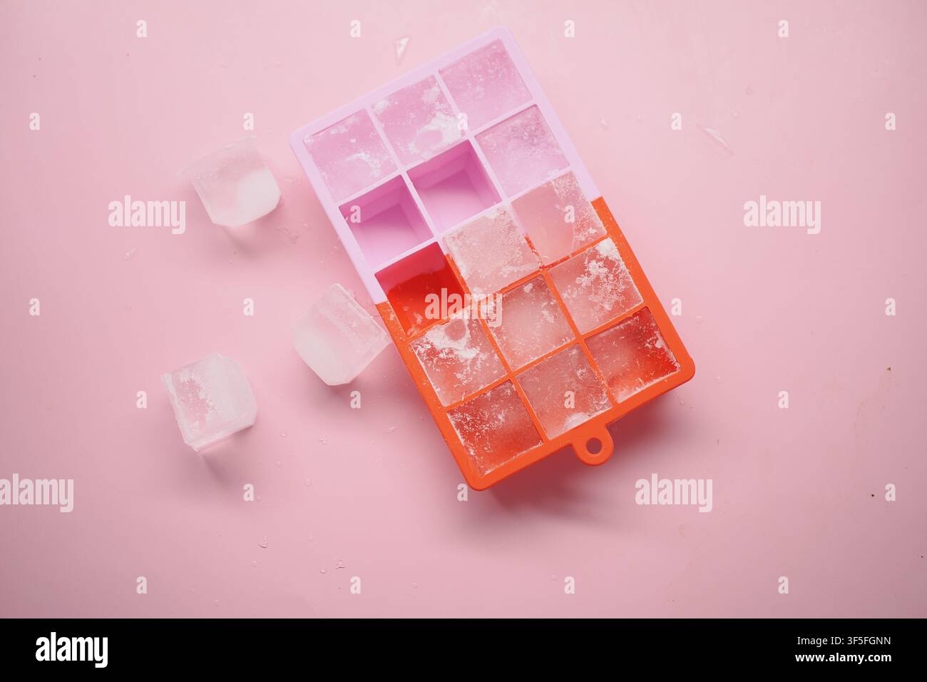 Eiskübelschale mit Eiswürfeln auf einem rosa Hintergrund Stockfoto