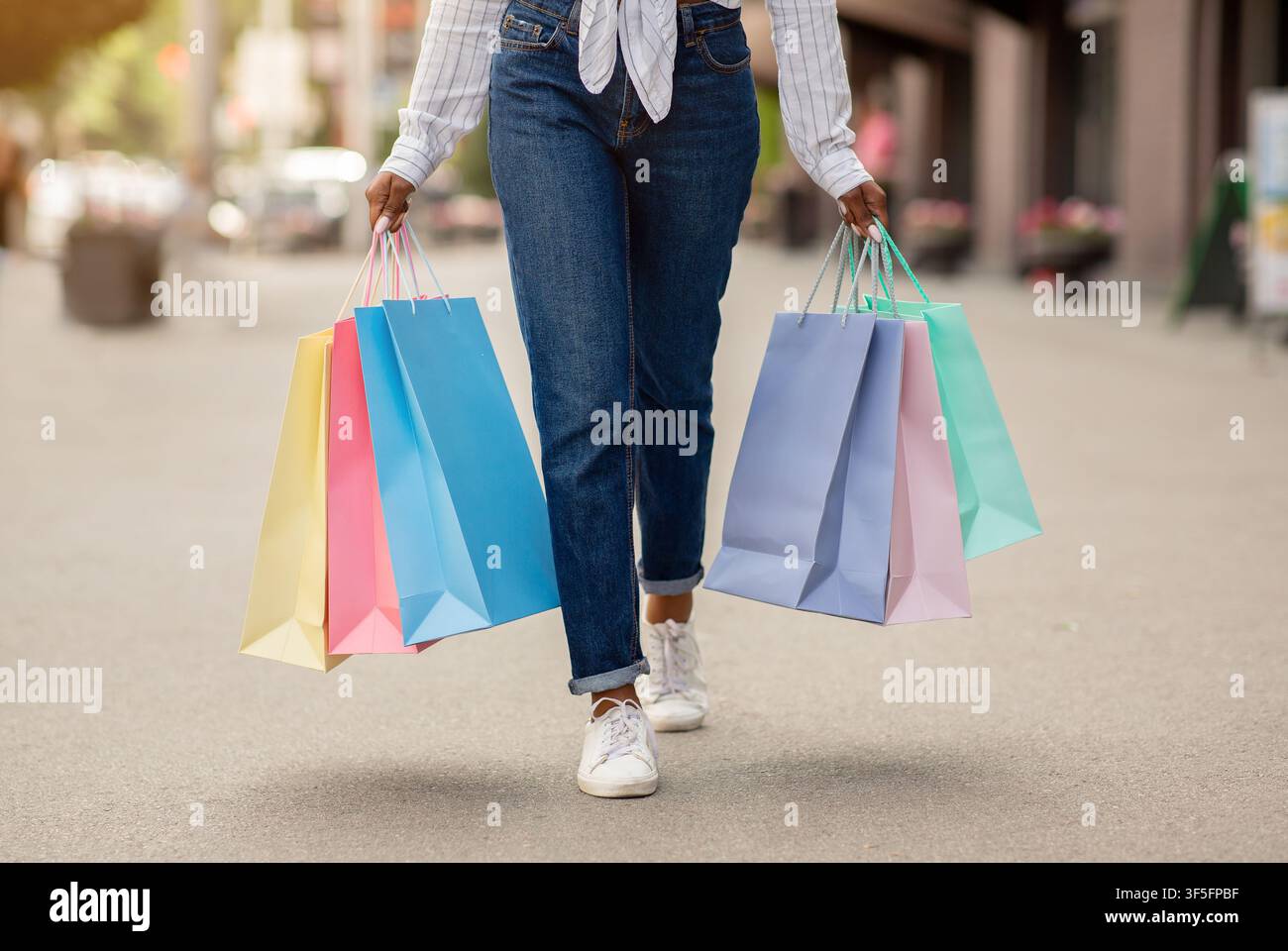 Einkaufen mit Boni und Geschenken. afroamerikanische Frau mit vielen Taschen geht auf der Straße Stockfoto