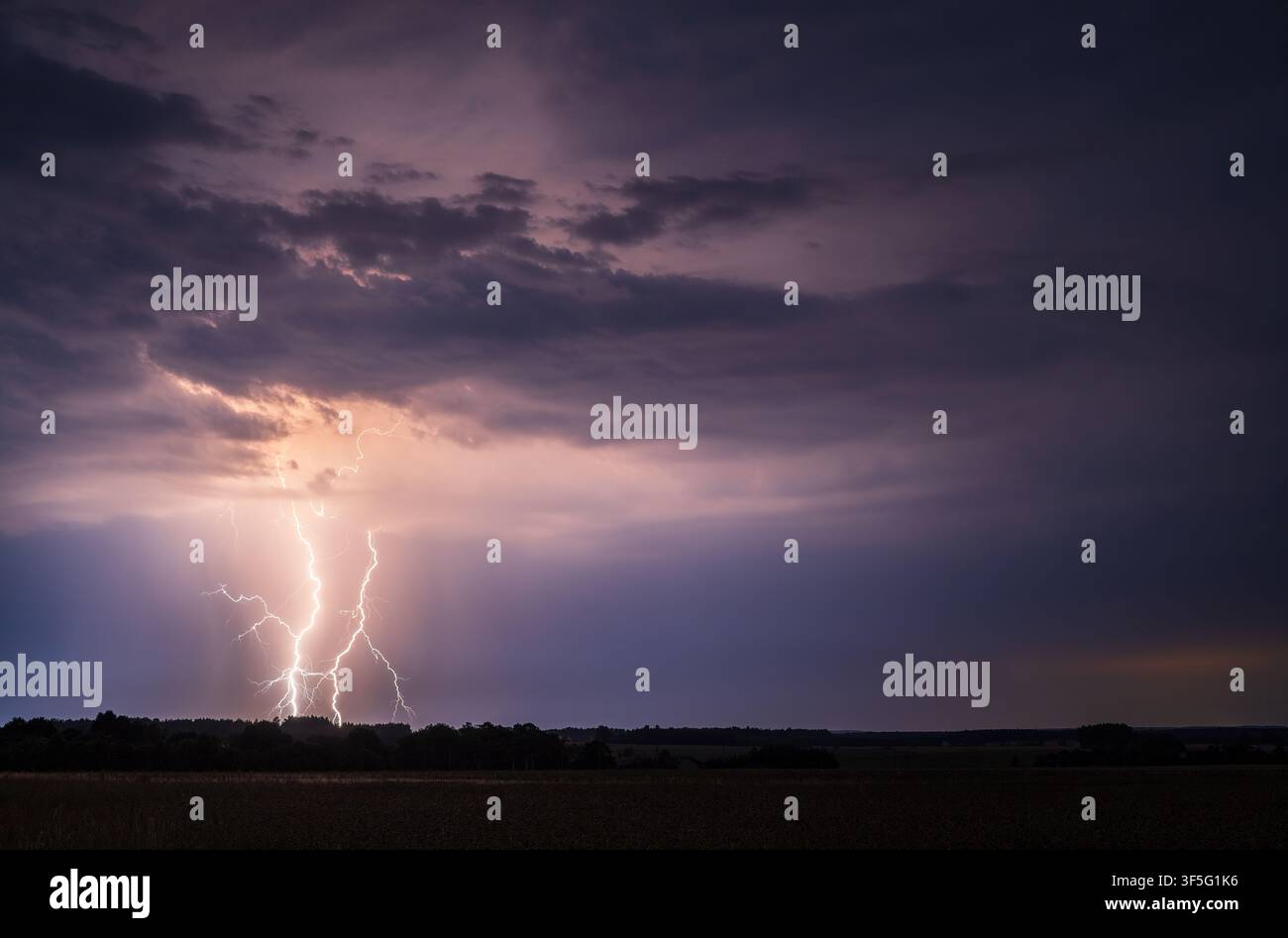 Mächtiger Blitzschlag von der Wolke zum Boden über einer ländlichen Landschaft bei Nacht Stockfoto