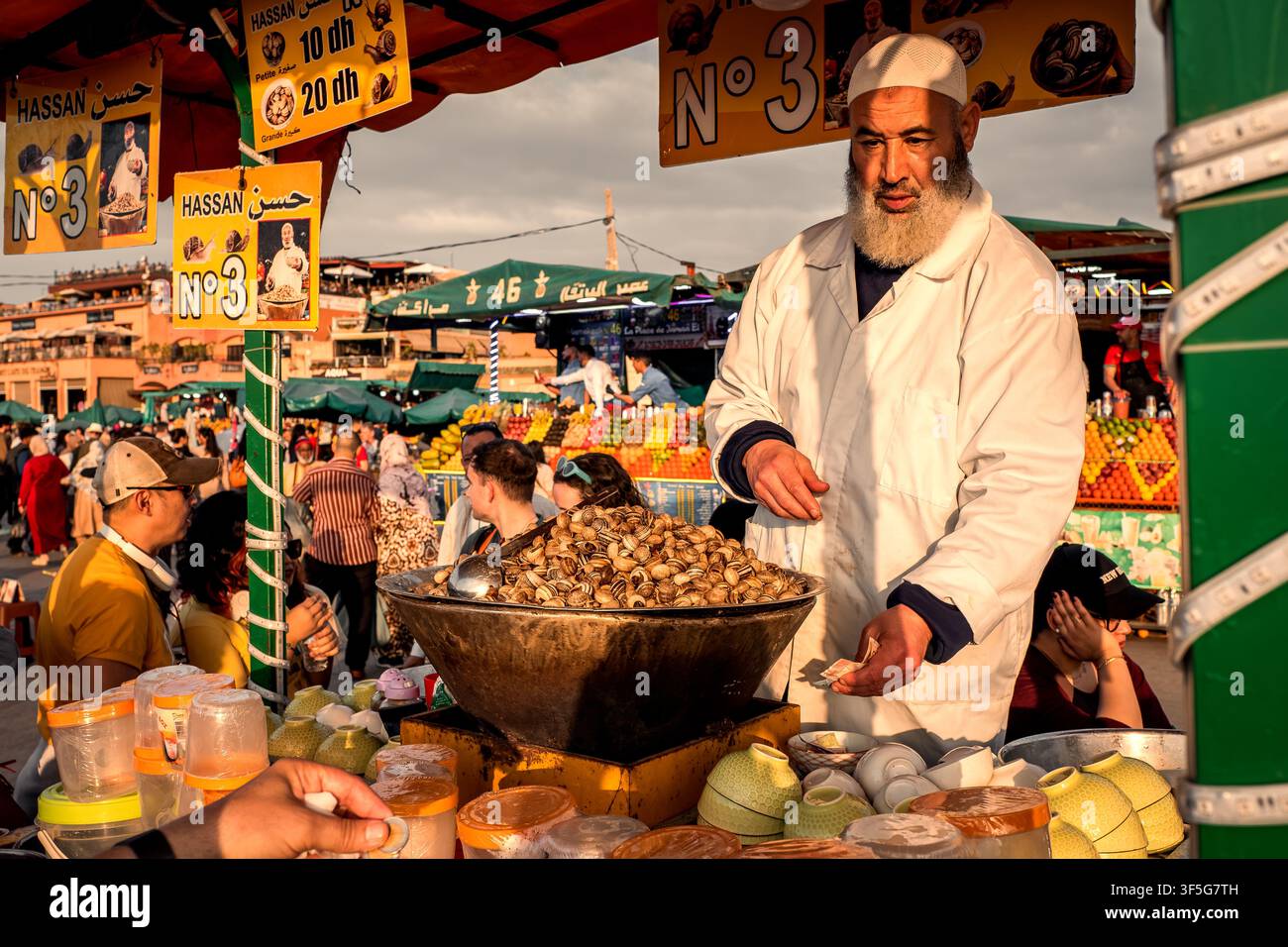 Wunderschöne Abendansicht eines Kochs, der frische Schnecken an Touristen und Einheimische auf dem Jemaa el-Fnaa-Platz im Medina-Viertel von Marrakech, Marokko, verkauft Stockfoto