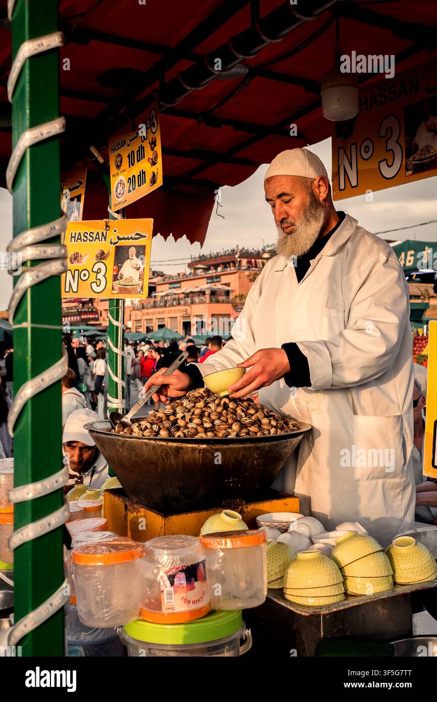 Wunderschöne Abendansicht eines Kochs, der frische Schnecken an Touristen und Einheimische auf dem Jemaa el-Fnaa-Platz im Medina-Viertel von Marrakech, Marokko, verkauft Stockfoto