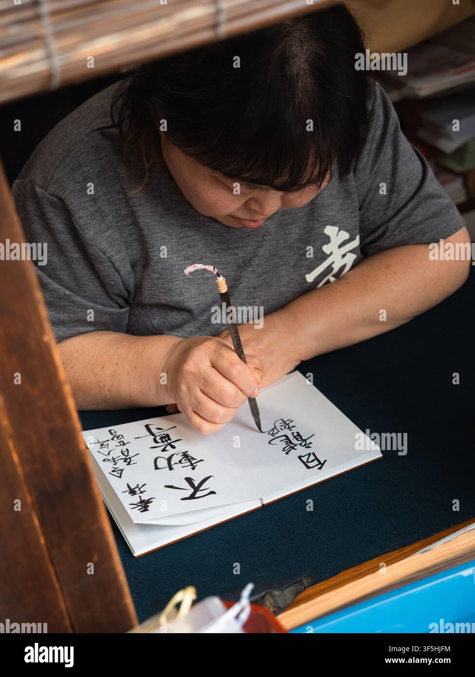 Frau schreibt japanische Kalligraphie mit einem Pinsel an einem Schreibtisch in Higashiyama, Kyoto, Japan Stockfoto