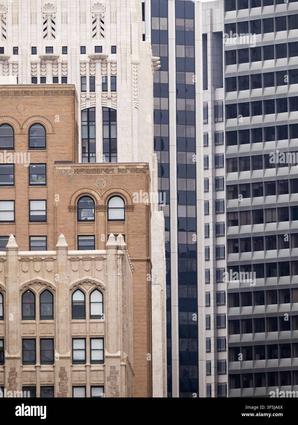 Nahaufnahme von gemischten historischen und modernen Gebäudefassaden in der Innenstadt von San Francisco, die gewölbte Fenster, detaillierte Mauerarbeit und Hochhausmuster zeigen Stockfoto