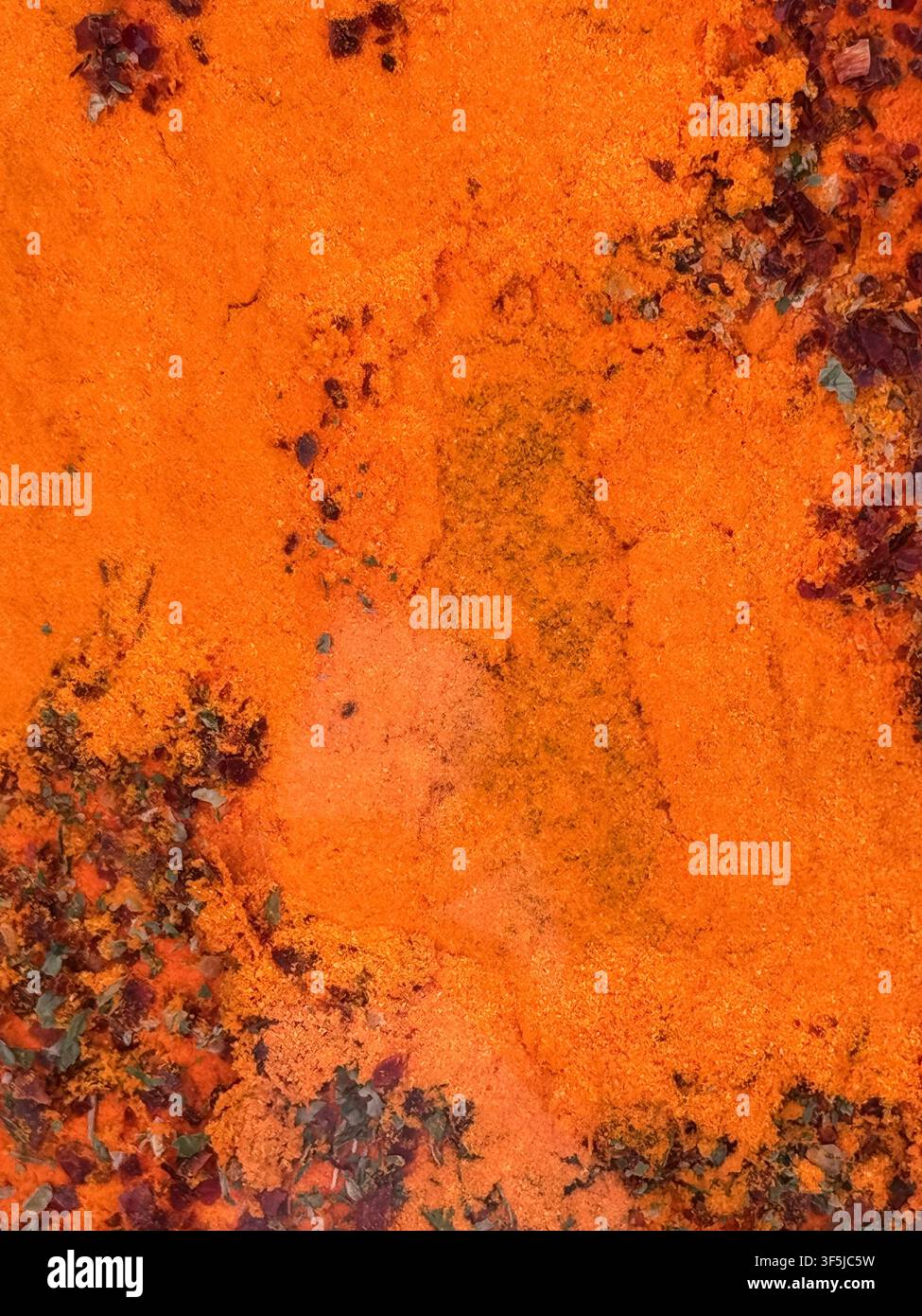 Nahaufnahme einer rostigen orangen Metalloberfläche mit abblätternder Farbe, dunklen Korrosionsstellen und rauer, verwitterter Textur. Abstrakter industrieller Hintergrund mit Stockfoto