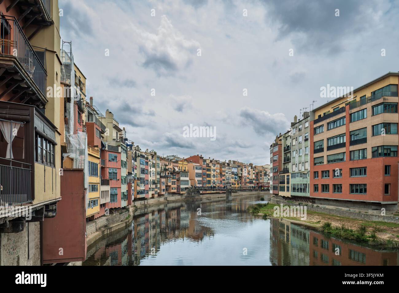 Farbenfrohe Häuser, die sich im Onyar-Fluss in der historischen Stadt Girona, Katalonien, Spanien, Europa, unter einem bewölkten Himmel spiegeln. Stockfoto