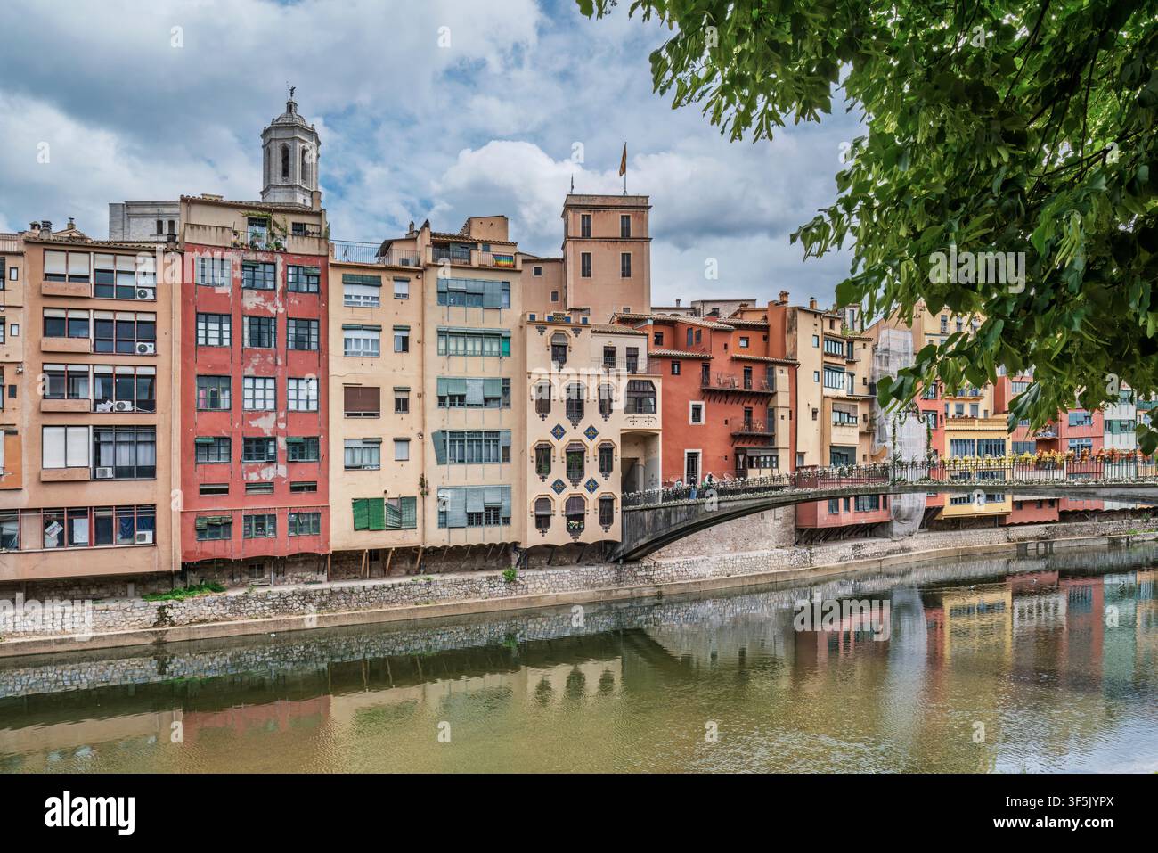 Farbenfrohe Uferhäuser, die sich im Onyar-Fluss in Girona, Katalonien, Spanien, Europa spiegeln, mit dem Kathedralturm und einer Fußgängerbrücke. Stockfoto