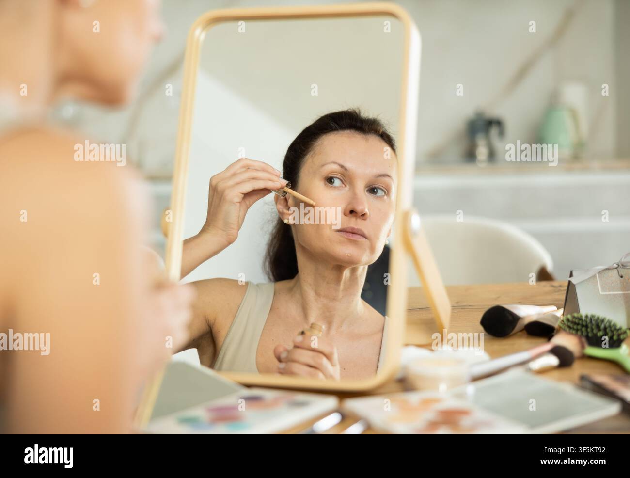 Frau mittleren Alters, die flüssige Foundation auf ihr Gesicht aufträgt Stockfoto