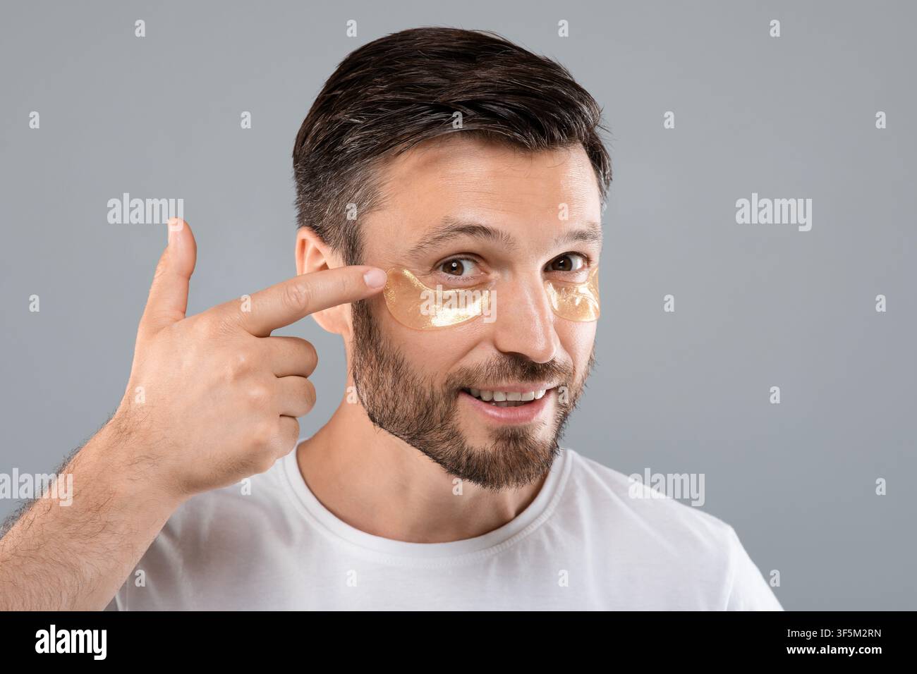 Hübscher Mann, der Augenflecken auf sein Gesicht anwendet Stockfoto