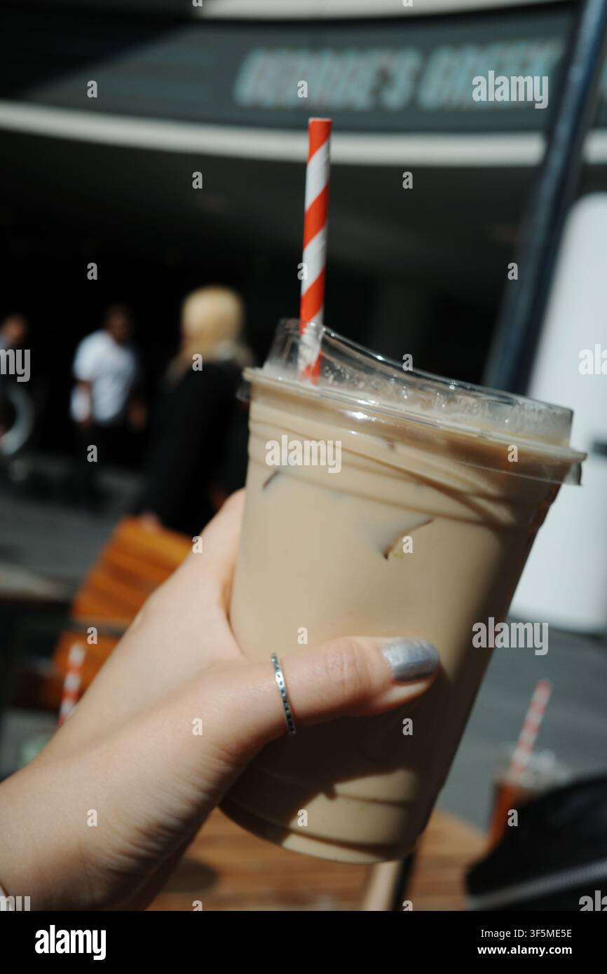 Hand, die ein Eiskaffee-Getränk mit einem gestreiften Strohhalm im Freien hält, Kalifornien Stockfoto