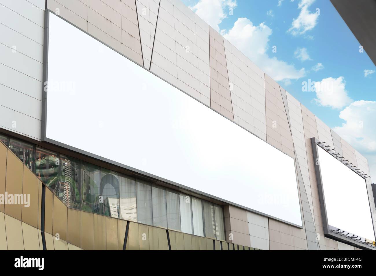 Breite leere Werbetafeln, die auf moderner urbaner Fassade unter blauem Himmel installiert sind, geeignet für Werbung, Branding, Promotion, Beschilderung, Kampagnenvisuals Stockfoto