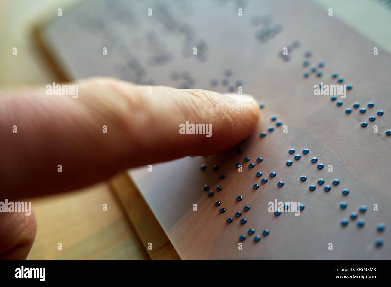 Person liest erhabene Braille-Zeichen durch Berühren, bewegt eine Fingerspitze über eine Seite, Nahaufnahme. Taktiles Lesen und zugängliche Kommunikation. Stockfoto