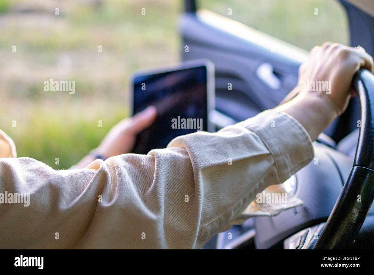 Hand hält Tablet während der Fahrt zu einer landwirtschaftlichen Feldinspektion. Konzept von Multitasking und digitaler Effizienz im Farmmanagement. Stockfoto