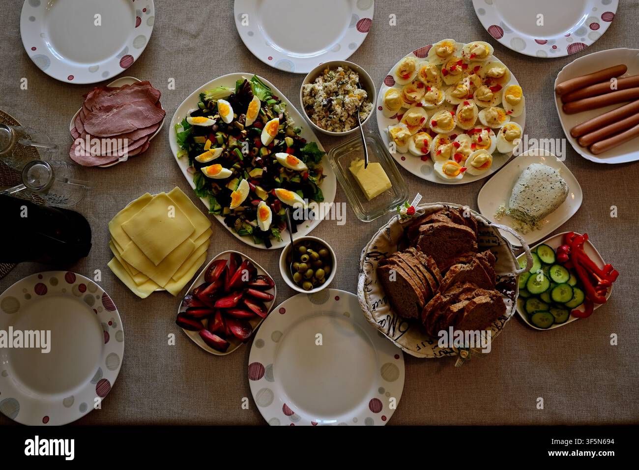 Familien-Buffet-Tisch mit gefüllten Eiern, Salat, Brot und Wurst zum gemeinsamen Essen. Stockfoto