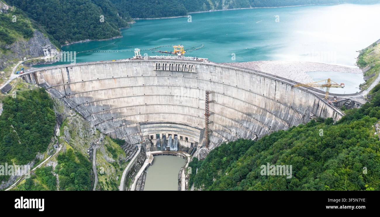 Luftbild des Enguri-Staudamms des Überlaufbeckens und der gebogenen Betonstruktur zur Wasserregulierung, Hydroelektrikeringenieurwesen, Hochwasserschutz und Infrastruktur. Stockfoto