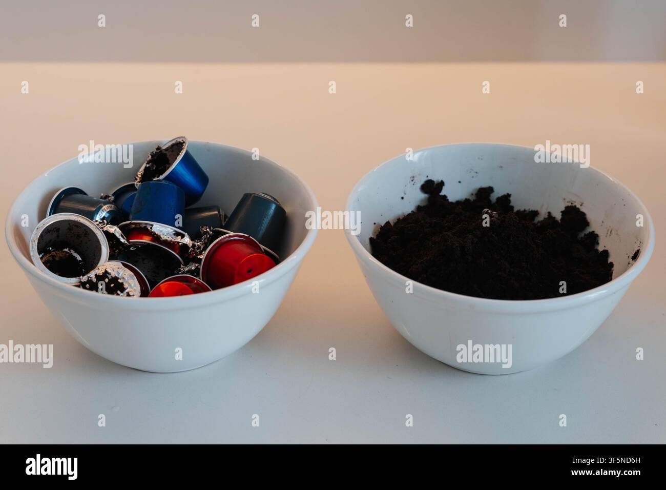Gebrauchte Kaffeekapseln und abgenutzter Kaffeesatz, die zur Mülltrennung in verschiedene Schalen aufgeteilt sind. Organischen Kaffeemüll von Aluminiumverpackungen trennen Stockfoto