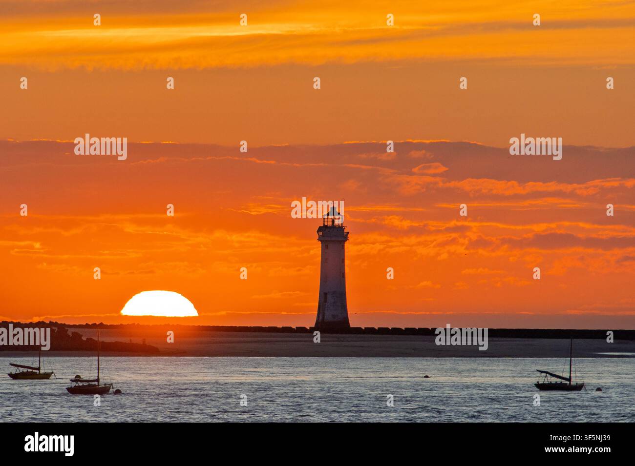 New Brighton Perch Rock Leuchtturm vor einer hellroten untergehenden Sonne an der Mersey Stockfoto