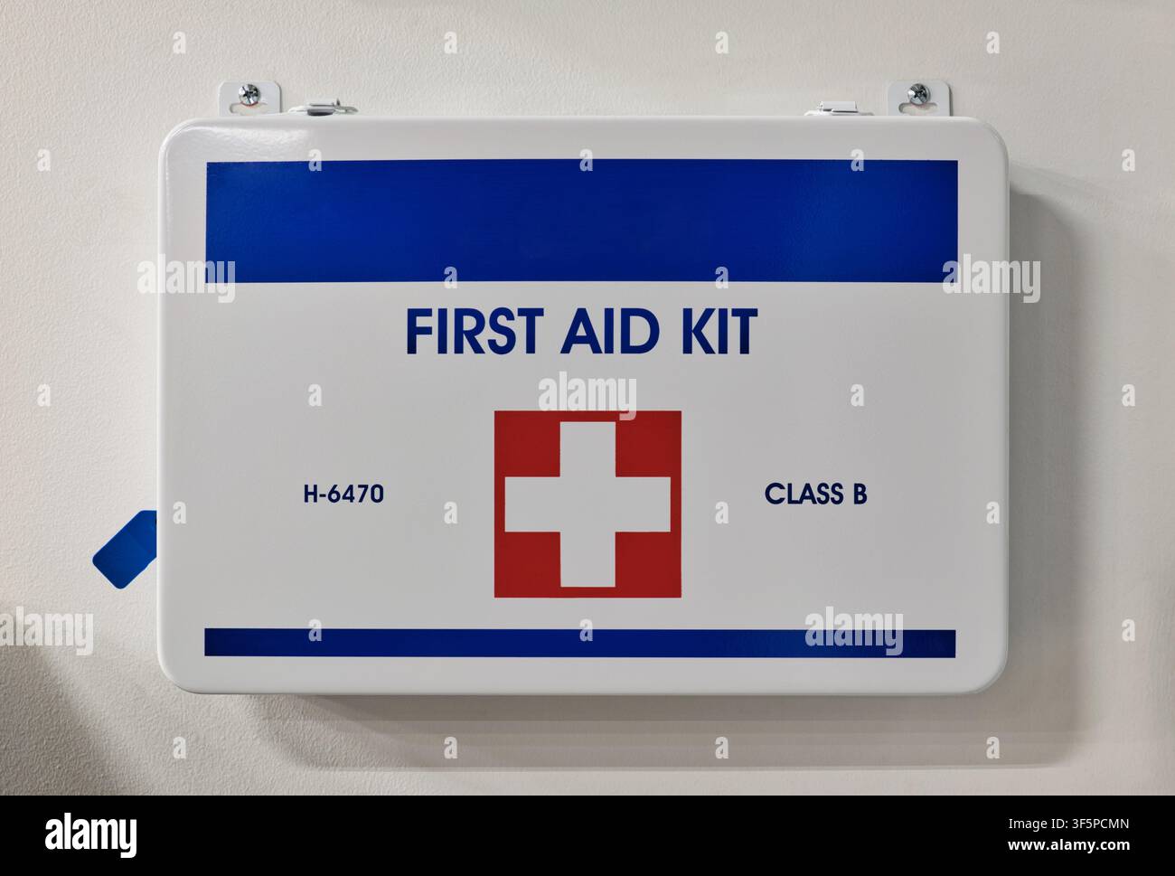 Erste-Hilfe-Kasten mit medizinischen Hilfsmitteln, an einer Wand in einer Arbeitsumgebung befestigt. Stockfoto