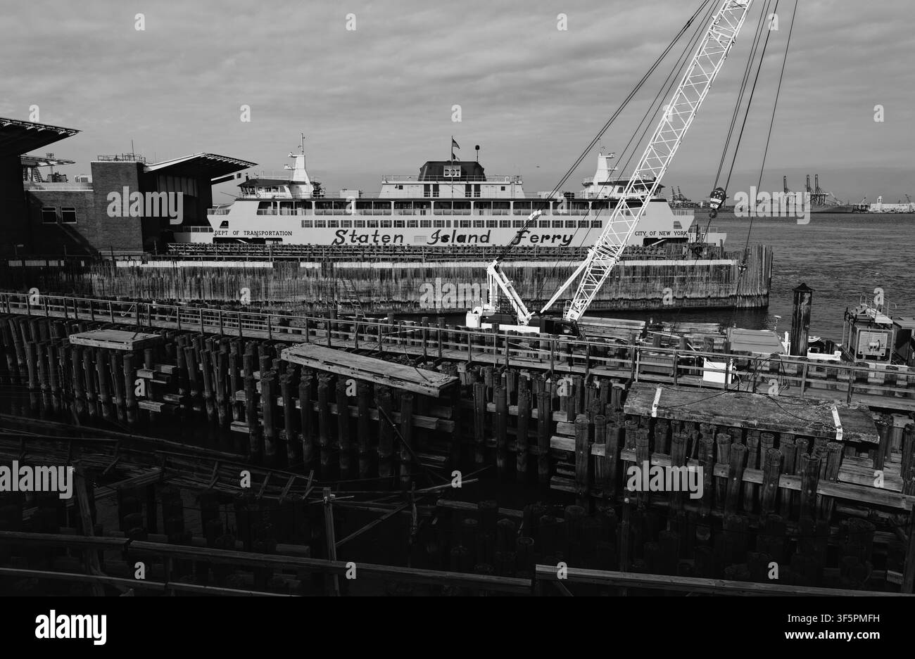 Ein verwitterter Kai aus Pfählen und Takelage bereitet die Bühne für die angedockte Staten Island Fähre Stockfoto