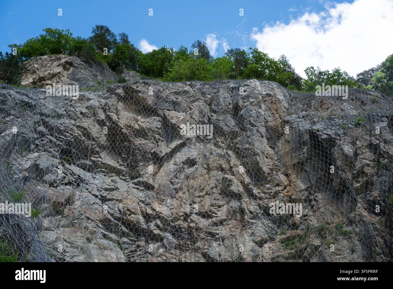 Schwere Stahlringnetz-Barriere und Drahtgitter-Vorhang, die auf einer steilen felsigen Klippe zur Steinschlagabwehr und Landschutz installiert sind. Stockfoto