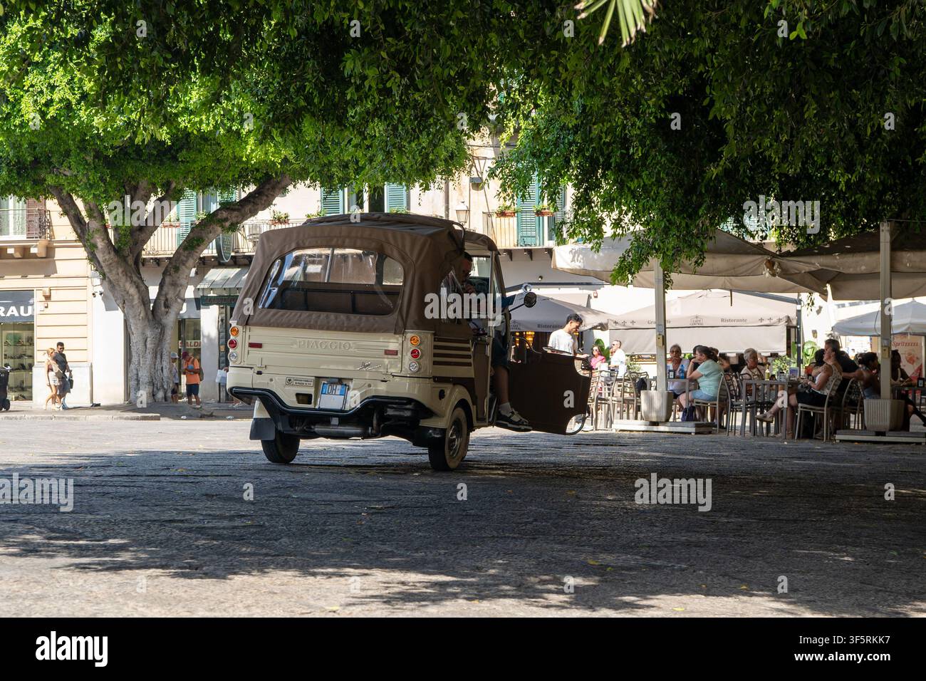 Geparkter Vintage-beiger Piaggio Ape Calessino Dreirad auf einem europäischen Stadtplatz. Stockfoto