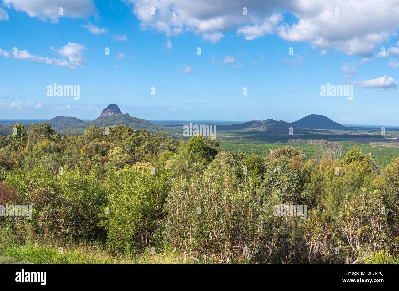 Weite Panoramaansicht der Glass House Mountains unter einem blauen bewölkten Himmel Stockfoto