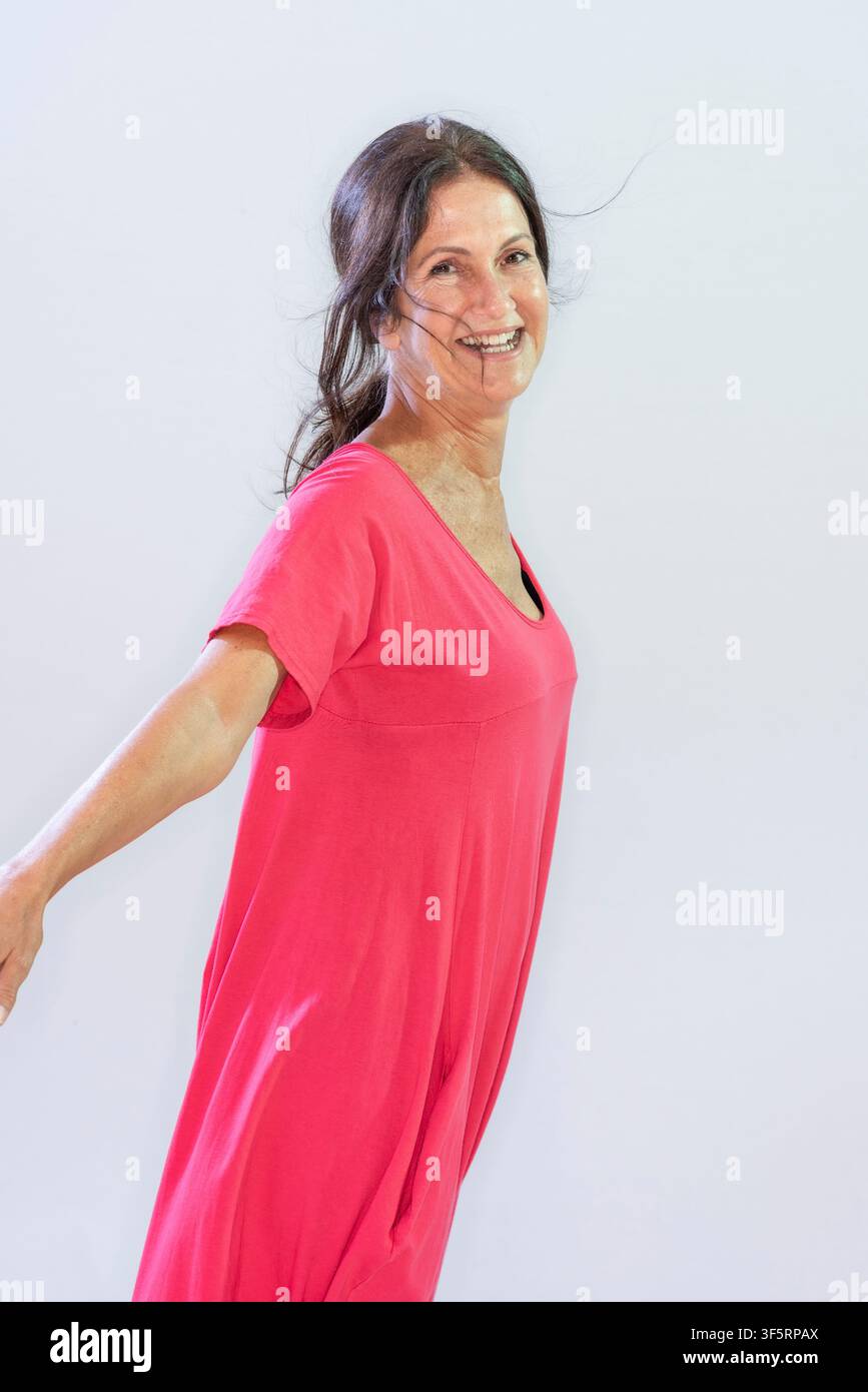 Vanessa Altin steht mit offenen Armen und einem Lächeln im Gesicht. Sie posiert vor einem hellen Hintergrund und zeigt einen natürlichen Look. Die Szenerie wirkt bri Stockfoto