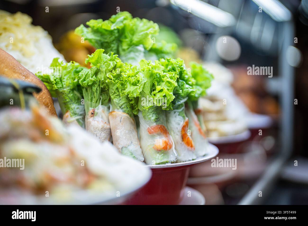 Auslage eines handgemachten Fast-Food-Tellers mit Reispapier-Springrollen mit Kräutern und Garnelen auf dem Markt. Stockfoto