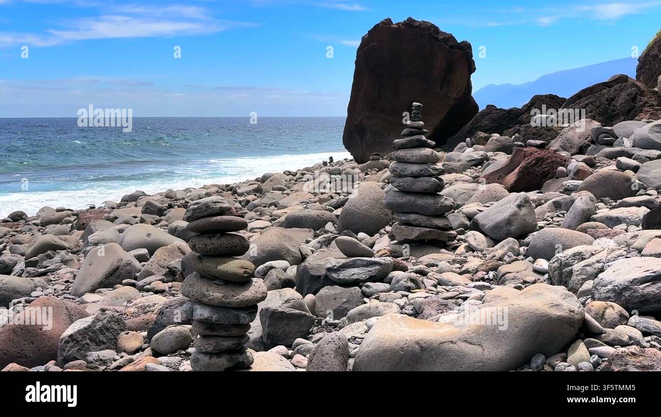 Steinhaufen, die auf einer felsigen vulkanischen Küste mit dem Atlantischen Ozean im Hintergrund auf der Insel Madeira balanciert sind. Stockfoto
