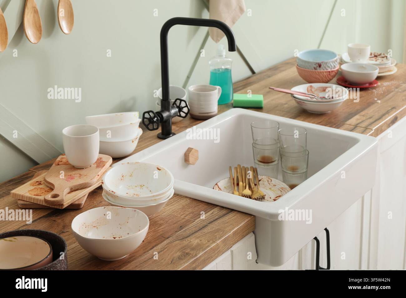 Unordentliche Küchenspüle und Arbeitsplatte voller schmutziger Geschirrspülen, Schüsseln, Gläser und Besteck nach einer Mahlzeit Stockfoto